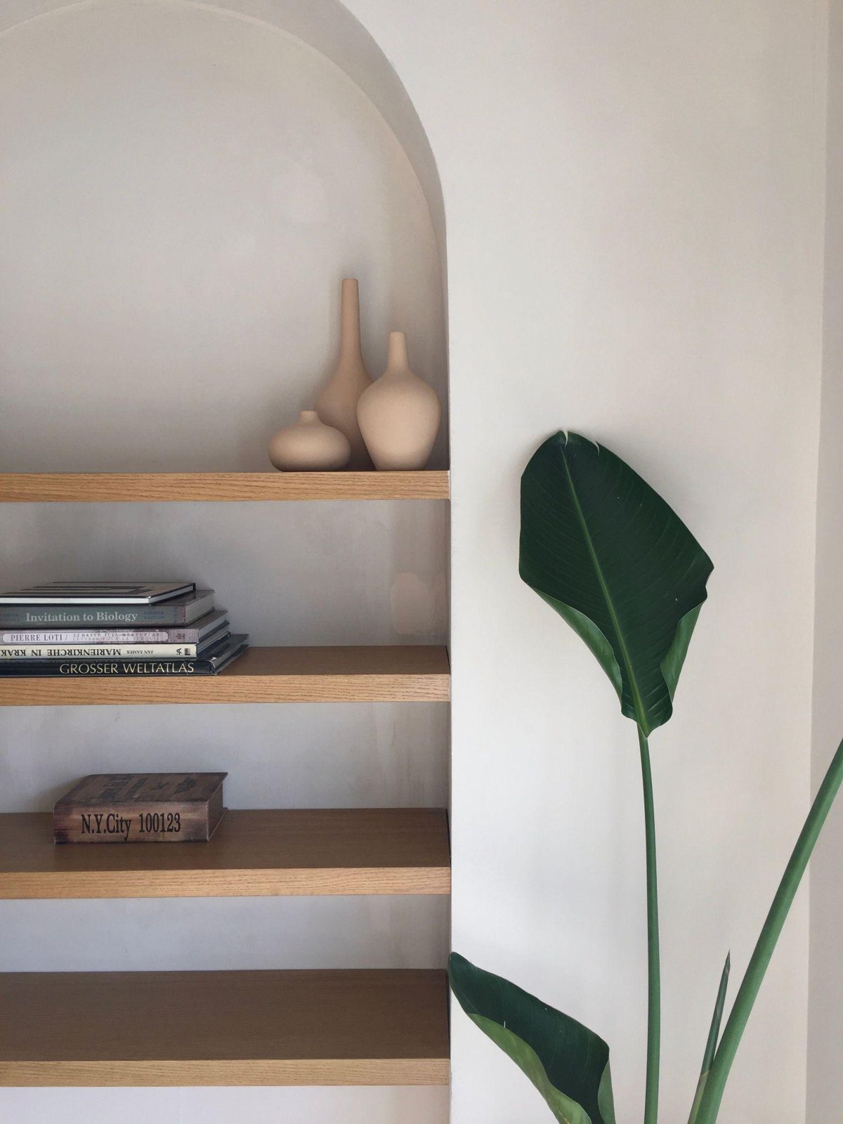 Estantería decorada con tres objetos de distintas alturas y ramas de eucalipto