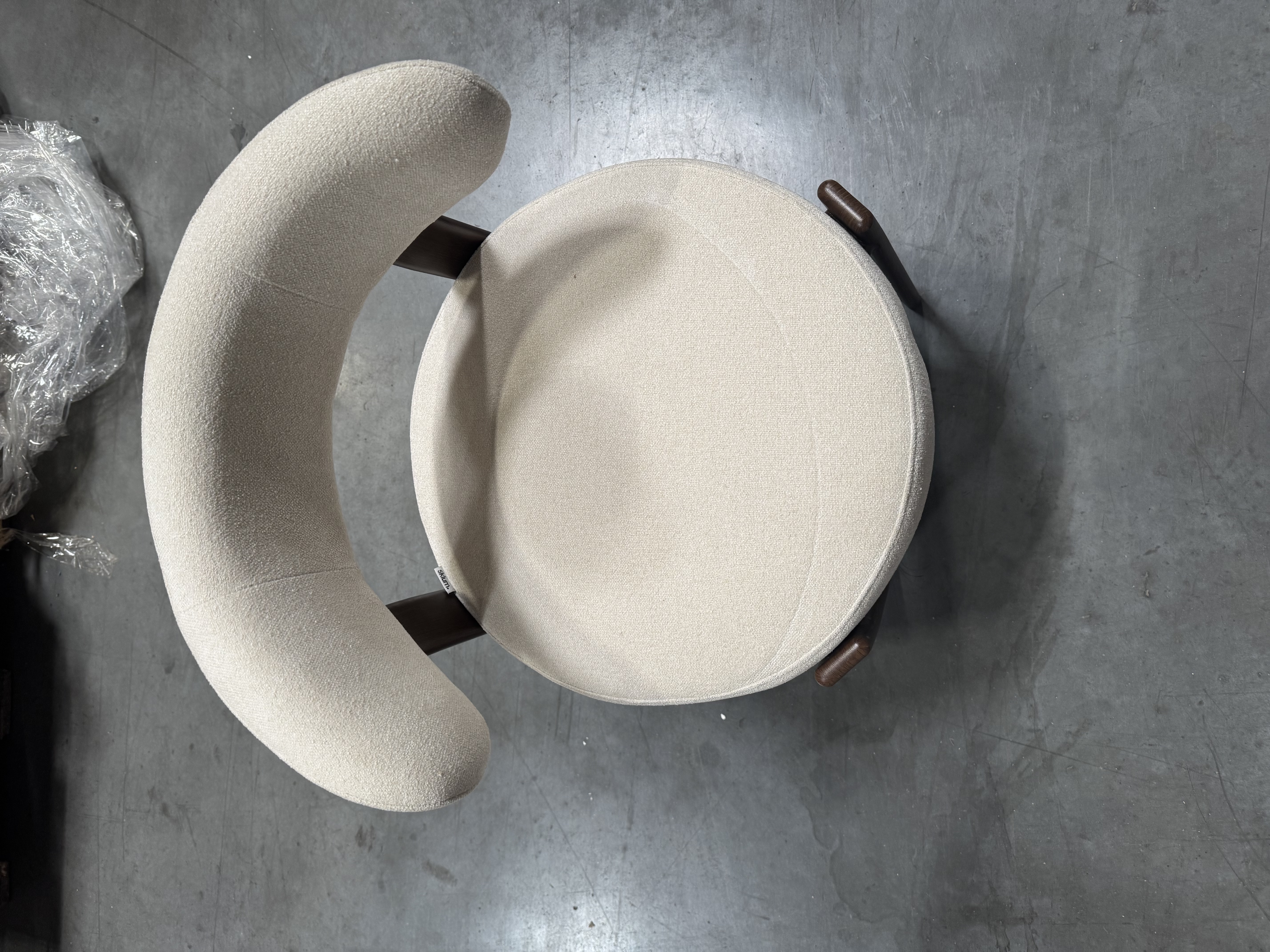 Sillón tapizado con respaldo curvo envolvente y estructura metálica