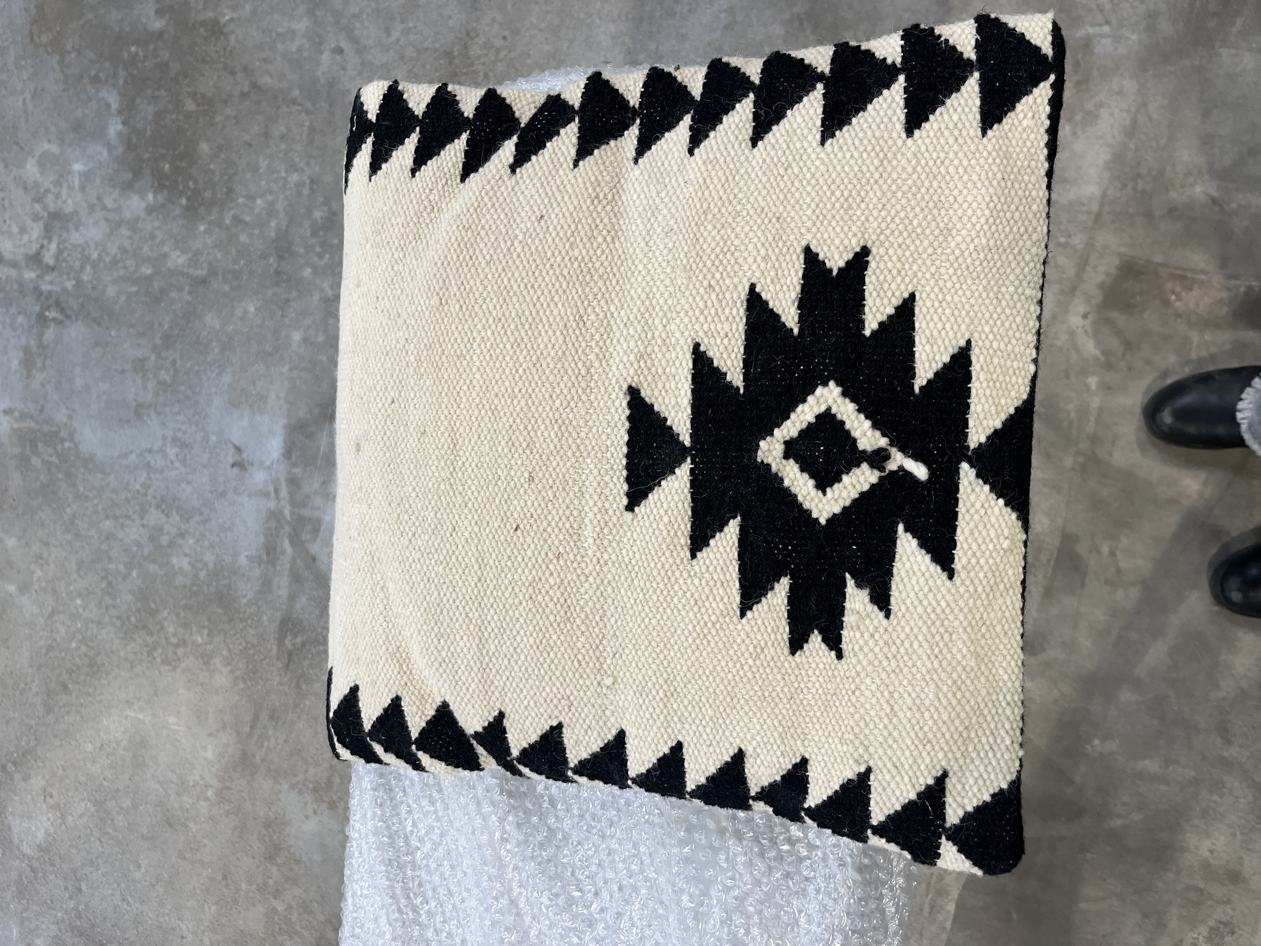 3 cojines blancos con cenefas negras y alfombra a juego