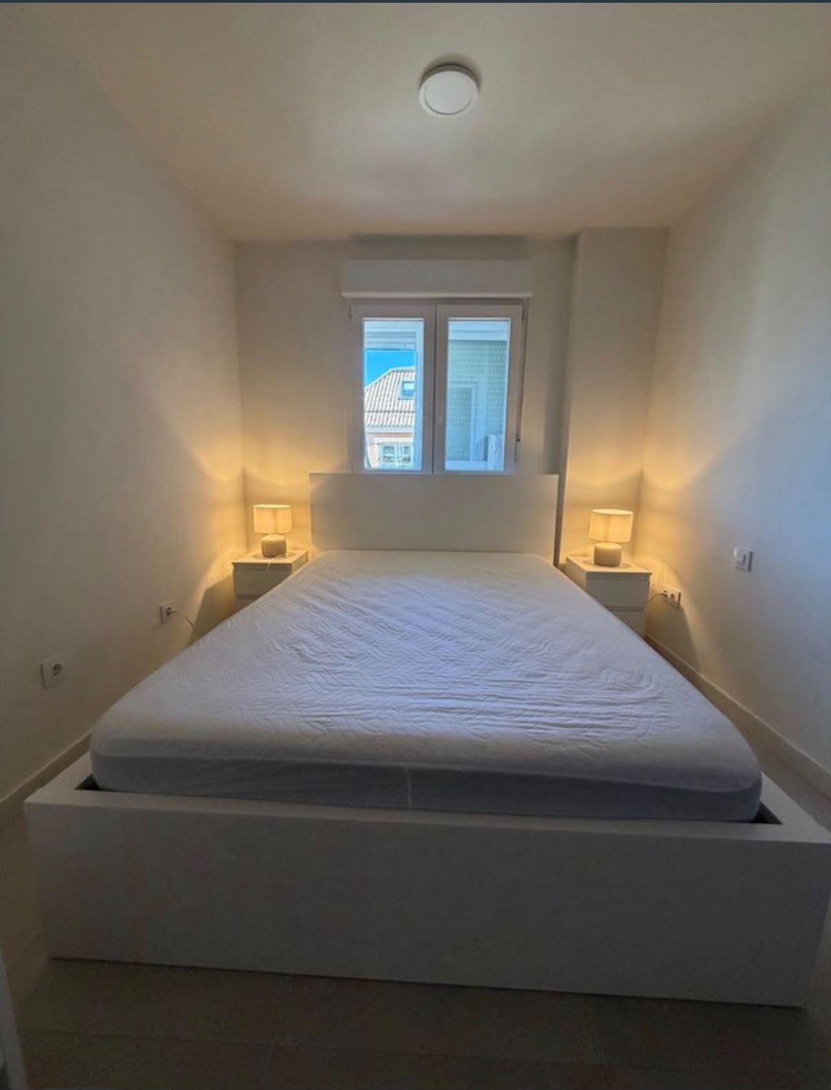 Cama de matrimonio blanca con dos mesitas de noche