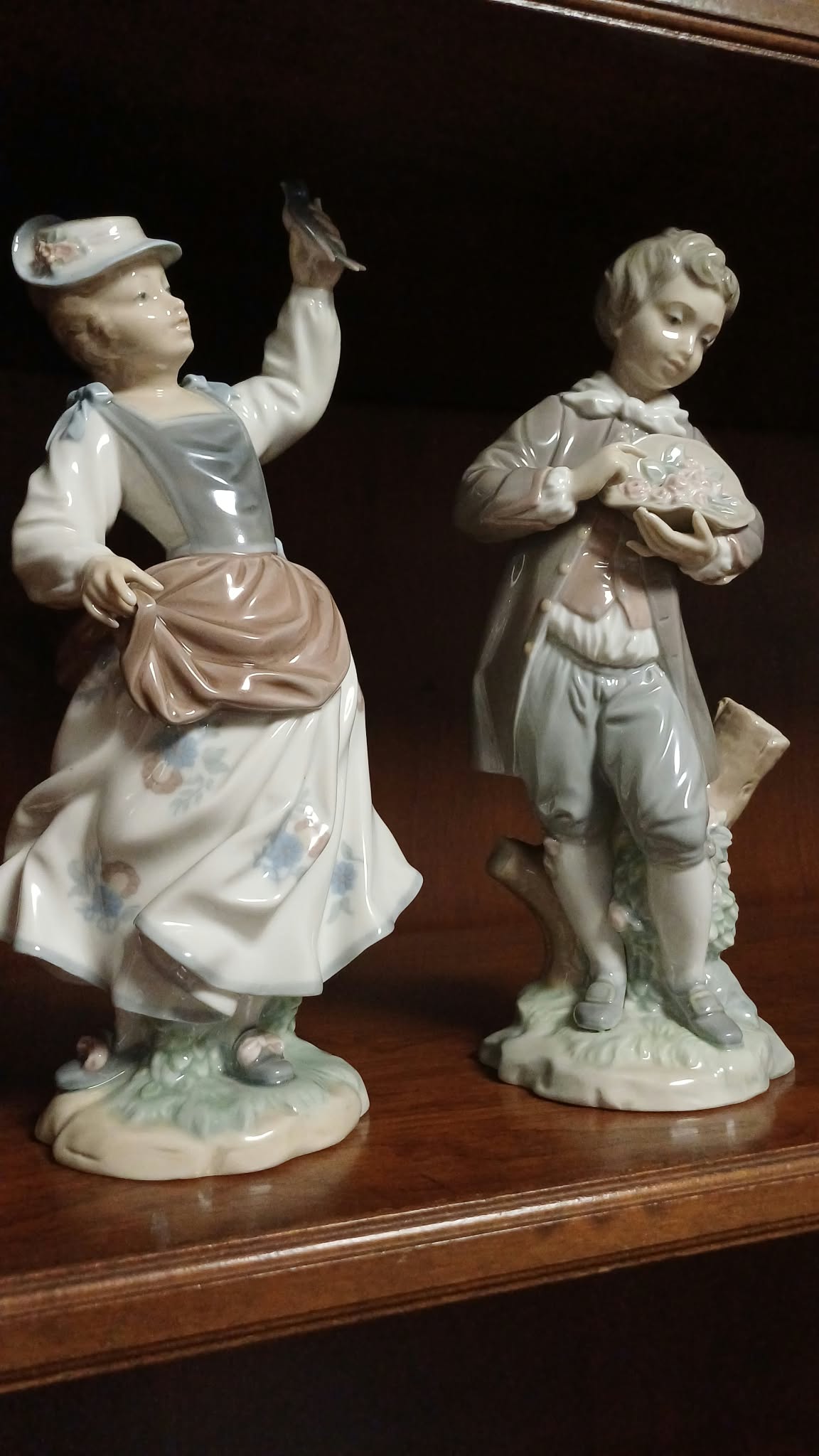 Pareja de figuras de porcelana Lladró – niña con pájaro y niño con flores. (set de 2) Años 70